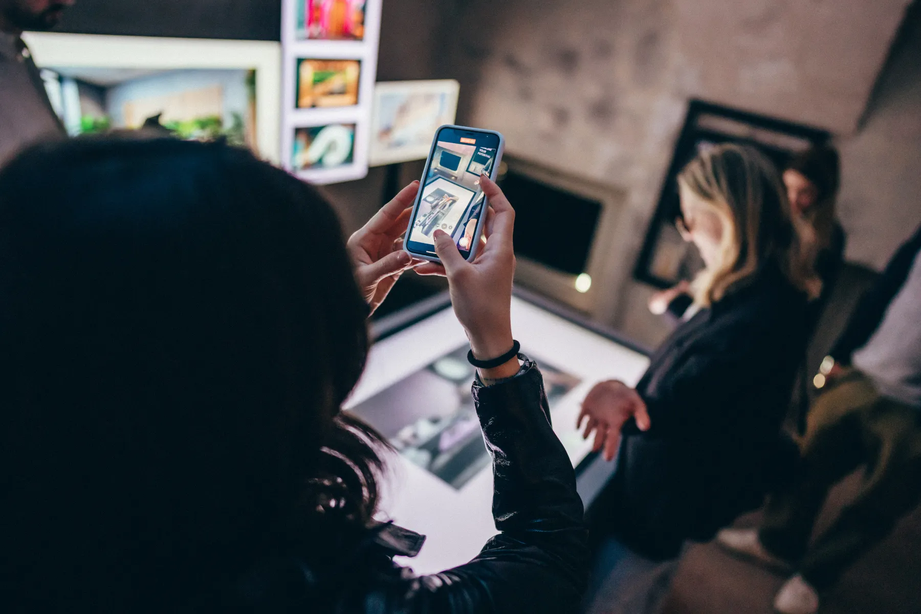 A visitor holding up a phone to photograph the generated imagery on the table below.